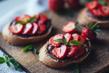 Strawberry bruschetta with chocolate paste and mint.Healthy thre