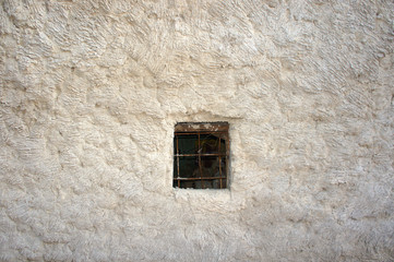 Small and dark window with bars in stone wall 