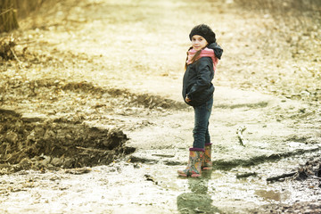 Young girl in rubber boots in the autumn forest