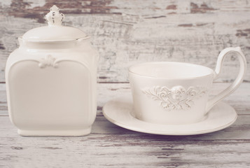 Simple rustic white and blue crockery, empty dishes. Large bowl, cup and porcelain jar with lid. Wooden background, shabby chic, vintage tinting
