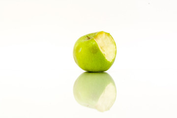 Bitten green apple with reflection on a white background