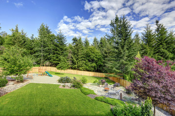 Large fenced backyard with patio and play set.