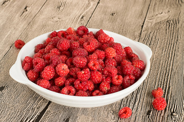 Ripe raspberries.   Juicy ripe raspberries in a white bowl on a wooden background.