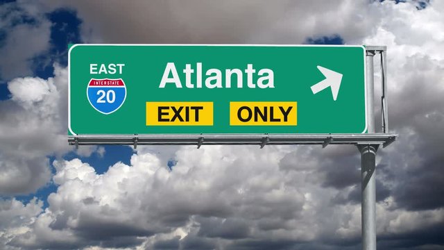 Atlanta Interstate 20 exit sign with time lapse clouds.