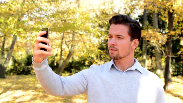 Young man stands in the woods and makes its selfie