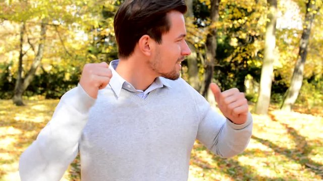 Young happy man cheerfully dances in the woods 