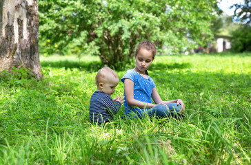 baby boy and little girl sitting playing on grass in park