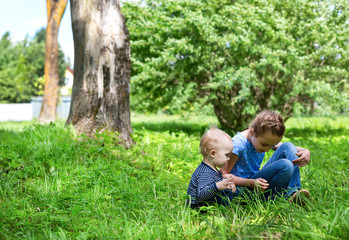 baby boy and little girl sitting playing on grass in park