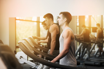 Fototapeta na wymiar group of men exercising on treadmill in gym