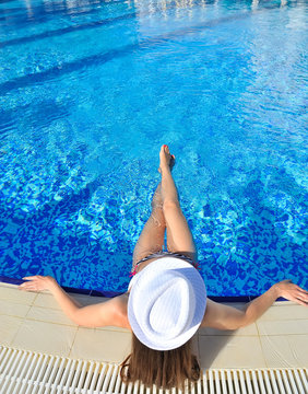 Beautiful woman white hat and bikini lying in a pool