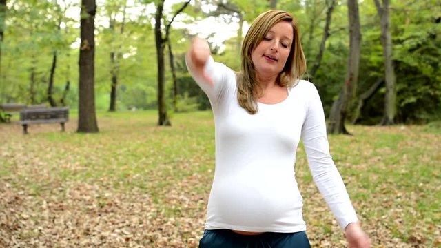 Young pretty pregnant woman disagrees and gives thumbs down in park