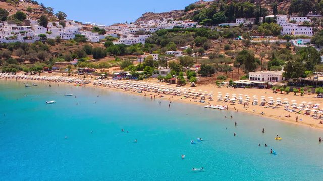 timelapse tourists relax on sunny day at beach. Many people on holiday in Lindos , Greece. Mediterranean sea.