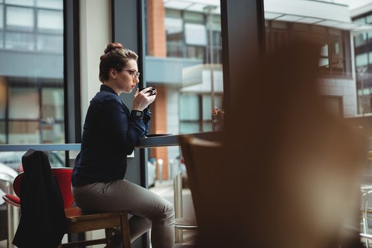 Woman drinking coffee while sitting on chair