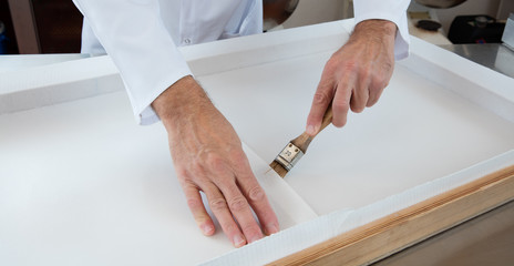 anonymous hands preparing a wooden frame with edible rice paper