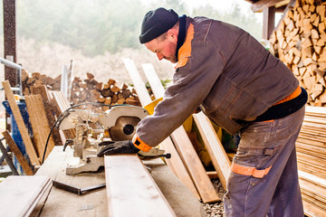 Carpenter working. Man cutting plank by circular saw.