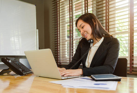woman working in office and talking telephone and smiling