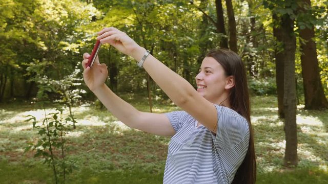 Happy young woman taking selfie with the smartphone in the park