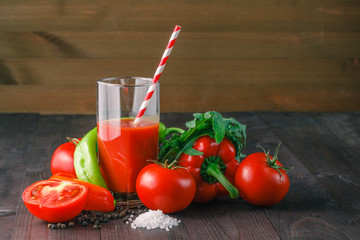 Glass of tasty tomato juice and fresh tomatoes on table