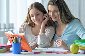 mother helping her  daughter with homework