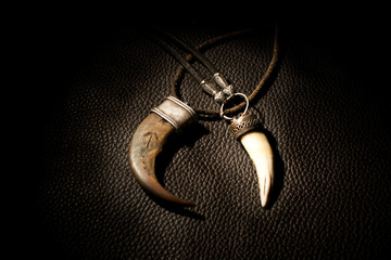 Carved tusk pendant of bone on the leather background