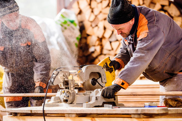 Carpenter working. Man cutting plank by circular saw.