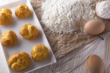 Tasty eclairs, eggs, flour and handle mixer.