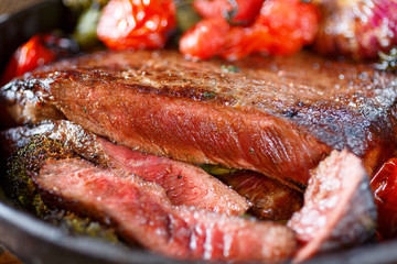 Beef steak medium rare with vegetables on a cast iron skillet. Still life of meat and vegetables in a low key. Rustic style food. covered with a rustic table