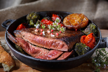 Beef steak with vegetables on a cast-iron frying pan