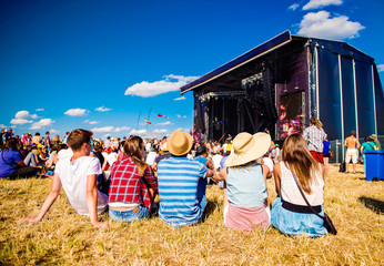 Teenagers, summer music festival, sitting in front of stage