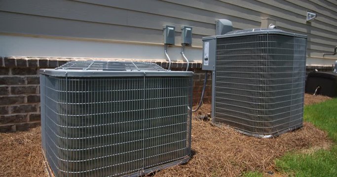 Two Air Conditioning Units on Side of Home Rising Shot. camera rises on two central air conditioning units on the side of a home. Camera tilts down to show the top of the units
