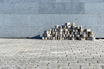 The sidewalk blocks which are accurately put near a granite wall