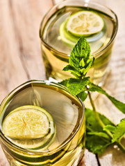Alcohol drink. On wooden boards are two glasses with alcohol green transparent drink. A drink number seventeen mojito cocktail with lime and mint leaf . Top view. Country life. Light background.