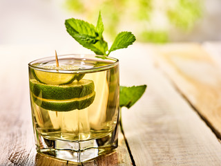 Alcohol drink. On wooden boards is glass with alcohol green transparent drink. A drink number...