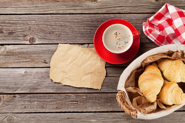 Fresh croissants and coffee on wooden table