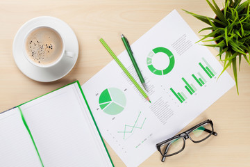 Office workplace with charts, plant and notepad