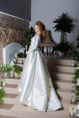 beautiful sweet girl elegant bride in an elegant wedding dress standing on the stairs