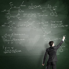 Scientist writing formulas on chalkboard