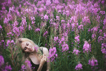 beautiful girl in black dress sitting in a field of lupine flowers