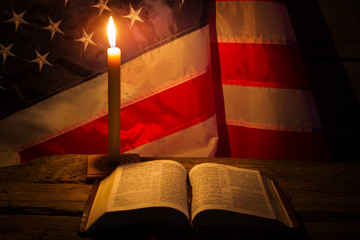 Burning candle and open book. America's flag behind burning candle. Night at old church. Never lose...