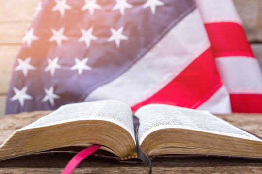 Open book and american flag. Open book on wooden surface. Value your independence. Freedom for every man. - Powered by Adobe