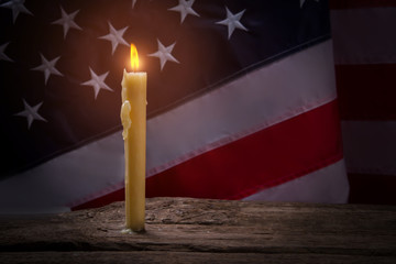 America's flag by candlelight. Burning candle on wooden surface. Light will show the way. For the...