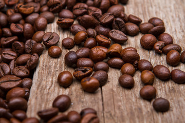 Coffee beans on wooden background. Brown coffee seeds. Old table with coffee grains. Imported coffee from India.