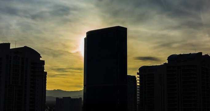 Hotel Silhouette from Setting Sun Backlit Time Lapse. the sun sets behind a tall hotel in Las Vegas Nevada. Sun flare hits the corner of the hotel and silhouettes the skyline of buildings.
