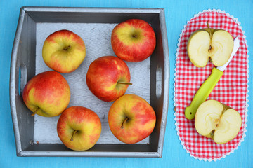 close up of red, yellow ,green apples in a wooden tray bowl with red white nostalgic  countryside checkered doily
