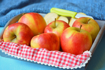 close up of red, yellow ,green apples in a wooden tray bowl with red white nostalgic  countryside checkered doily
