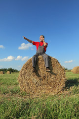Naklejka na ściany i meble Farmer at bale of hay in field speaking by phone and pointing