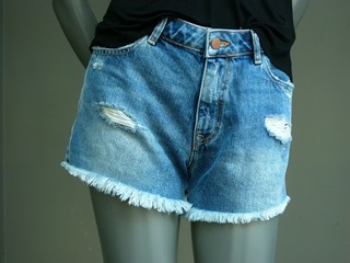 Sehr kurze Jeans mit Fransen als Hot Pants an einer grauen Schaufensterpuppe im Schaufenster einer...