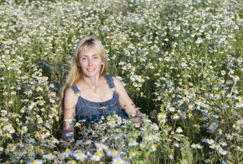 The happy young woman in the field  of camomiles..