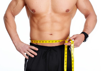 Man abdomen with measuring tape over blue background.
