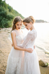 Fototapeta na wymiar Twin sisters in wedding dress on the seashore